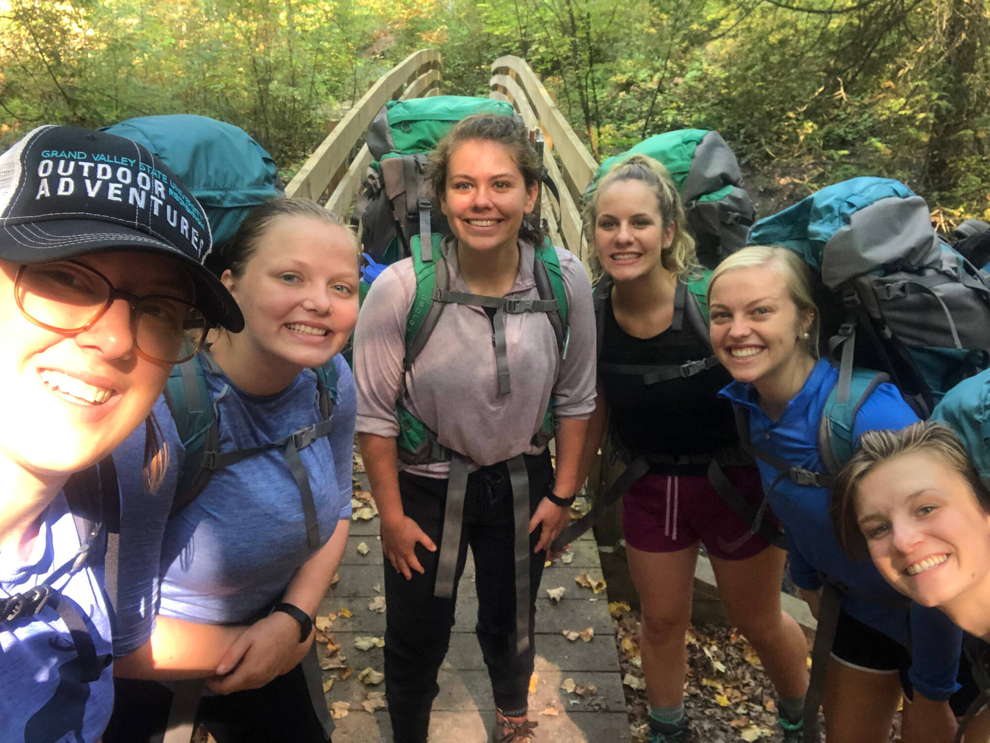 5 backpackers posing for a picture in front of a wooden bridge at the Manistee River Trail